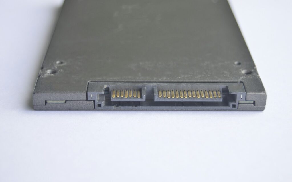 SSD 2,5 pouces posé à plat sur une surface blanche, connecteur SATA au premier plan, sans câble branché