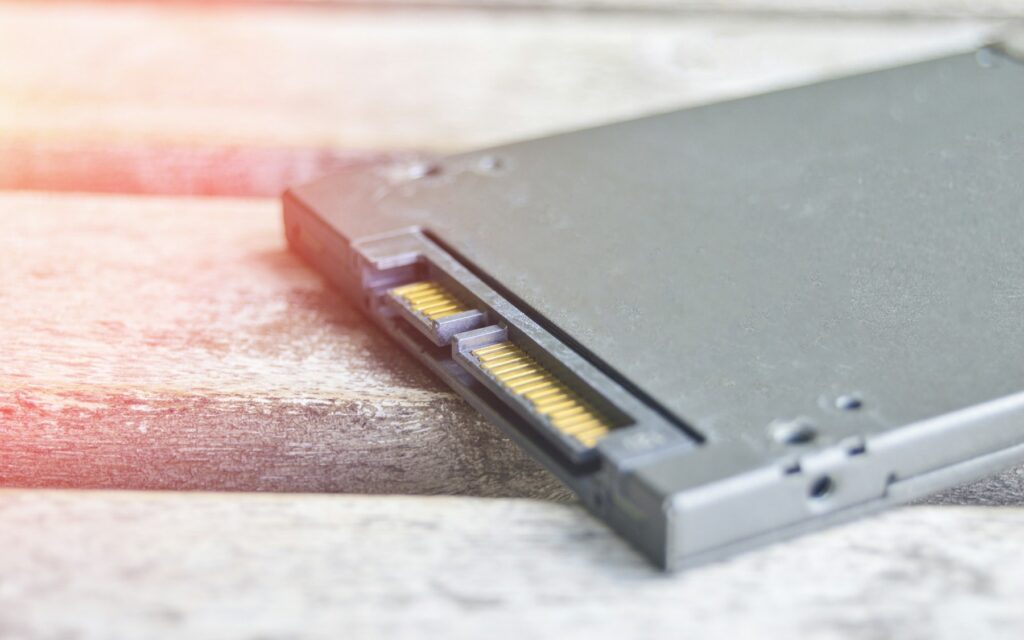 Gros plan sur le connecteur SATA doré d'un SSD 2,5 pouces posé sur du bois